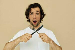 Attractive man in a white T-shirt with knife with fork Lifestyle unaltered photo