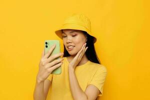 pretty brunette in a yellow hat and T-shirt talking on the phone studio model unaltered photo