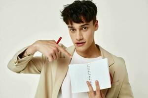 A young man in a beige suit copy-space notebook light background unaltered photo