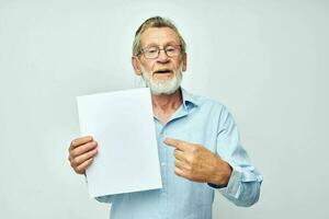 Portrait elderly man in a blue shirt and glasses a white sheet of paper unaltered photo