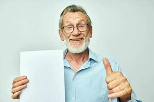 Senior grey-haired man blank sheet of paper gesture hands smile light background photo