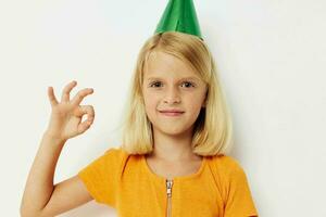 un niña con un verde gorra en su cabeza gestos con su manos foto