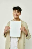 A young man in a beige suit copy-space folder with papers light background unaltered photo