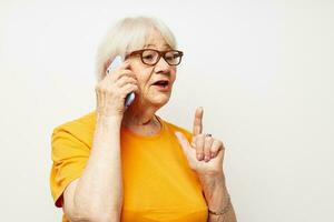 smiling elderly woman in a yellow t-shirt posing communication by phone close-up emotions photo