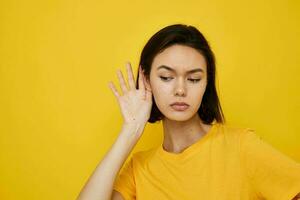 young woman yellow t-shirt summer style hand gesture yellow background photo