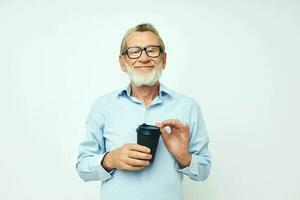 Photo of retired old man gestures with his hands a glass of drink light background