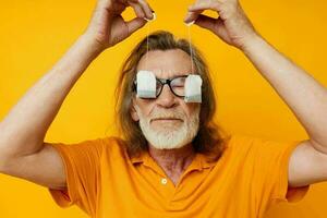 elderly man disposable tea bags near face yellow background photo