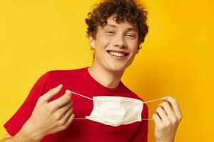 portrait of a young curly man wearing a red t-shirt medical mask on the face posing monochrome shot photo