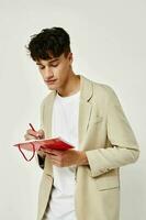 handsome guy posing with a notepad in a suit light background unaltered photo