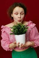 cheerful girl in a pink blouse pot with a flower in her hands red background photo