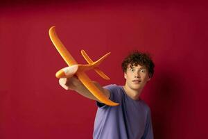 kinky guy with a toy plane in a purple t-shirt red background unaltered photo