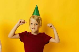 pequeño niña con un verde gorra en su cabeza amarillo antecedentes foto