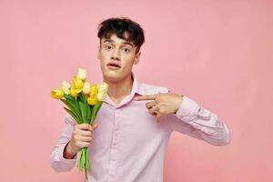 portrait of a young man Bouquet of yellow flowers romance posing fashion pink background unaltered photo