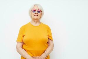 Portrait of an old friendly woman in a yellow t-shirt posing isolated background photo