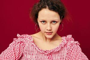 cute young girl in pink shirt gesturing with her hands studio red background photo