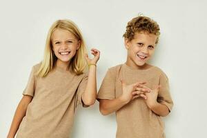 Portrait of cute children in beige t-shirts posing for fun isolated background photo