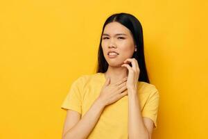 Charming young Asian woman in a yellow t-shirt holding his head discontent studio model unaltered photo