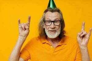 Senior grey-haired man in a yellow t-shirt with a cap on his head fun cropped view photo