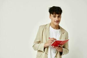 handsome guy posing with a notepad in a suit light background unaltered photo