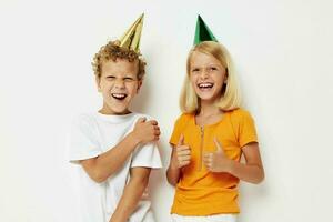 Boy and girl in multicolored caps birthday holiday emotion light background photo