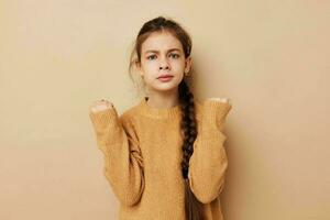 Portrait of happy smiling child girl long pigtail beige sweater grimace beige background photo