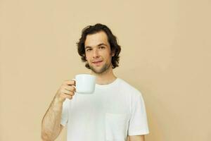 Attractive man with a white mug in his hands emotions posing beige background photo