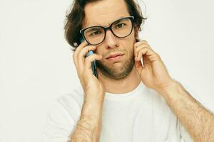 Attractive man in a white T-shirt communication by phone light background photo