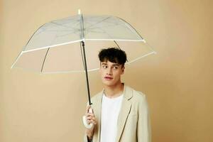 a man with an open umbrella in a jacket protection from the rain beige background photo