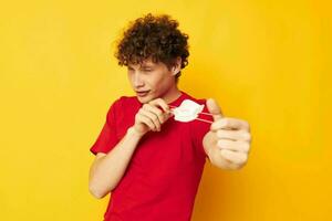 portrait of a young curly man in a red t-shirt medical mask protection yellow background unaltered photo