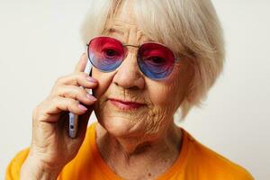 smiling elderly woman in casual t-shirt sunglasses talking on the phone close-up emotions photo