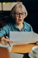 retrato de un mayor mujer sentado en un café con un taza de café y un ordenador portátil persona de libre dedicación trabajos inalterado foto