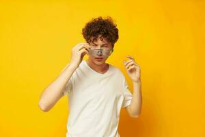 Young curly-haired man in blue glasses white t-shirt fashion modern style isolated background unaltered photo
