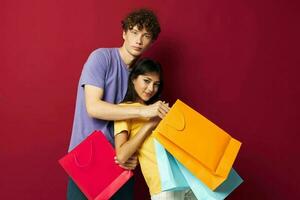 young boy and girl colorful bags shopping fun red background unaltered photo