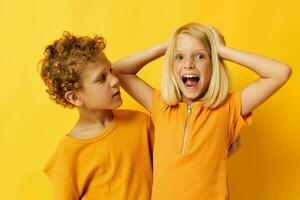 dos alegre niños en amarillo camisetas en pie lado por lado infancia emociones amarillo antecedentes foto