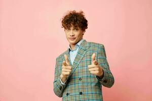 Young curly-haired man gesturing with his hands emotions checkered jacket pink background unaltered photo