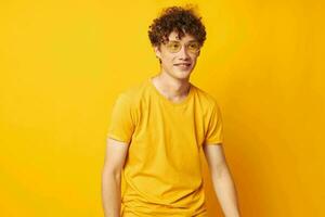 portrait of a young curly man yellow t-shirt glasses fashion hand gestures isolated background unaltered photo
