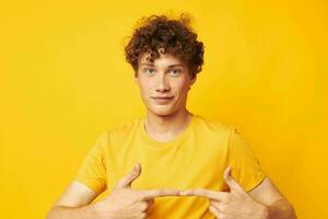 portrait of a young curly man yellow t-shirt fashion hand gestures isolated background unaltered photo