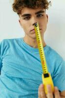 handsome guy yardstick in hand in blue t-shirts isolated background photo