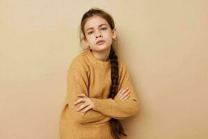 Portrait of happy smiling child girl long pigtail beige sweater grimace beige background photo