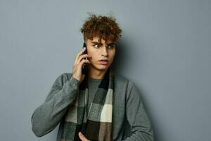 handsome guy in a plaid scarf talking on the phone posing emotions light background photo