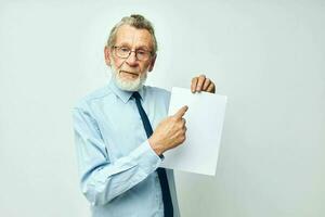 Senior grey-haired man holding documents with a sheet of paper light background photo