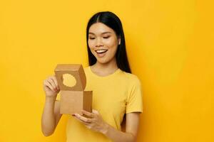 woman holding a small box gift yellow background photo