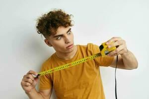 kinky guy measuring tape measure in yellow t-shirt light background photo