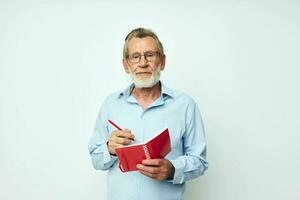 Photo of retired old man red notepad writing light background