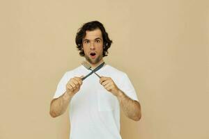 alegre hombre en un blanco camiseta con cuchillo con tenedor estilo de vida inalterado foto