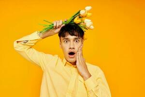 A young man give flowers wear spectacles yellow shirt yellow background unaltered photo