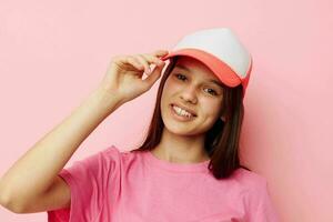 alegre joven niña con un gorra en su cabeza en un rosado camiseta foto