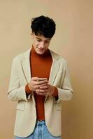 portrait of a young man in a beige jacket talking on the phone light background unaltered photo