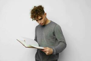linda chico con Rizado pelo con un libro en su manos formación foto