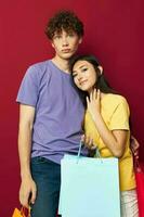 young boy and girl in colorful T-shirts with bags Shopping red background unaltered photo